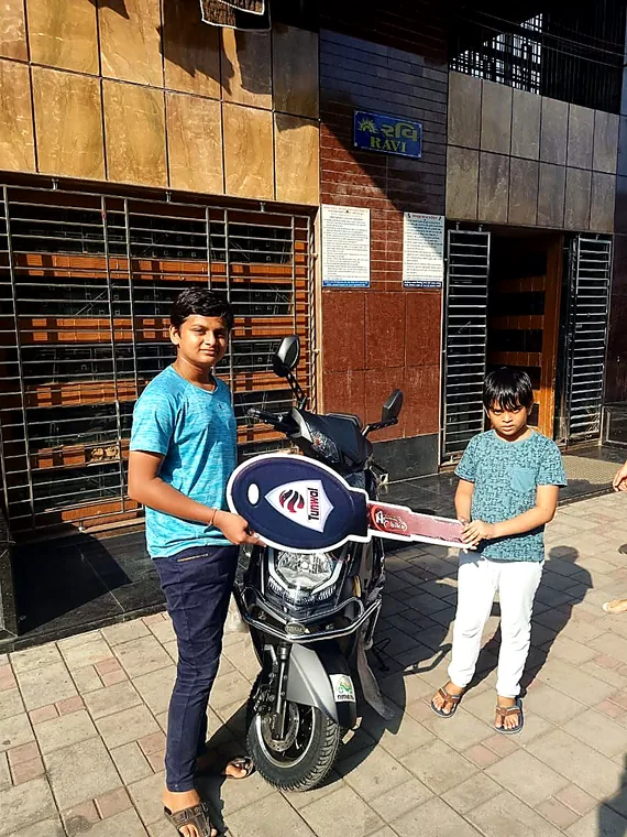 A young customer receiving the key to a new silver electric two-wheeler
