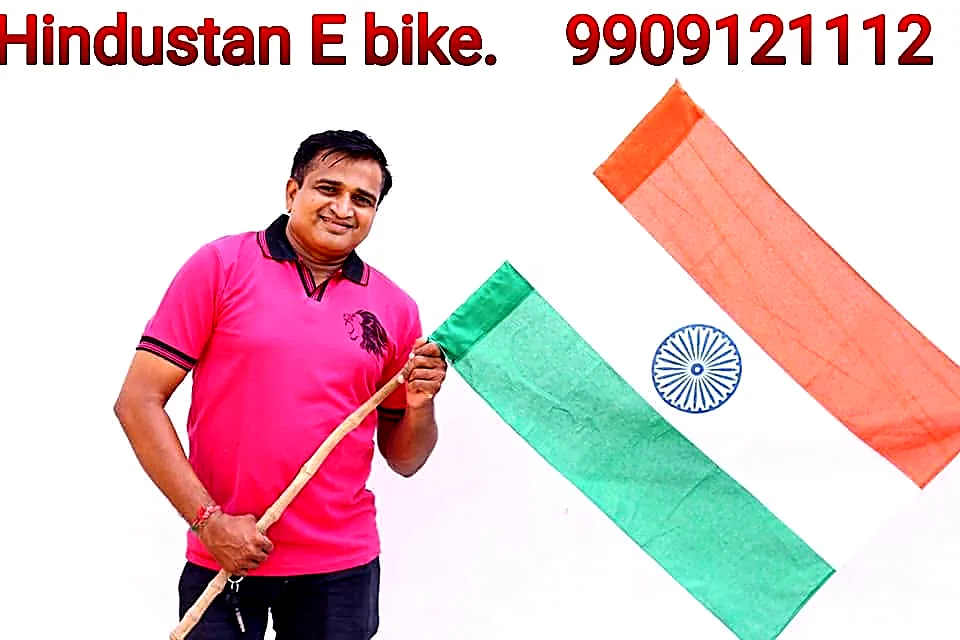 Proprietor Mahesh Jasani holding the Indian flag, with the Hindustan E-Bike name and phone number