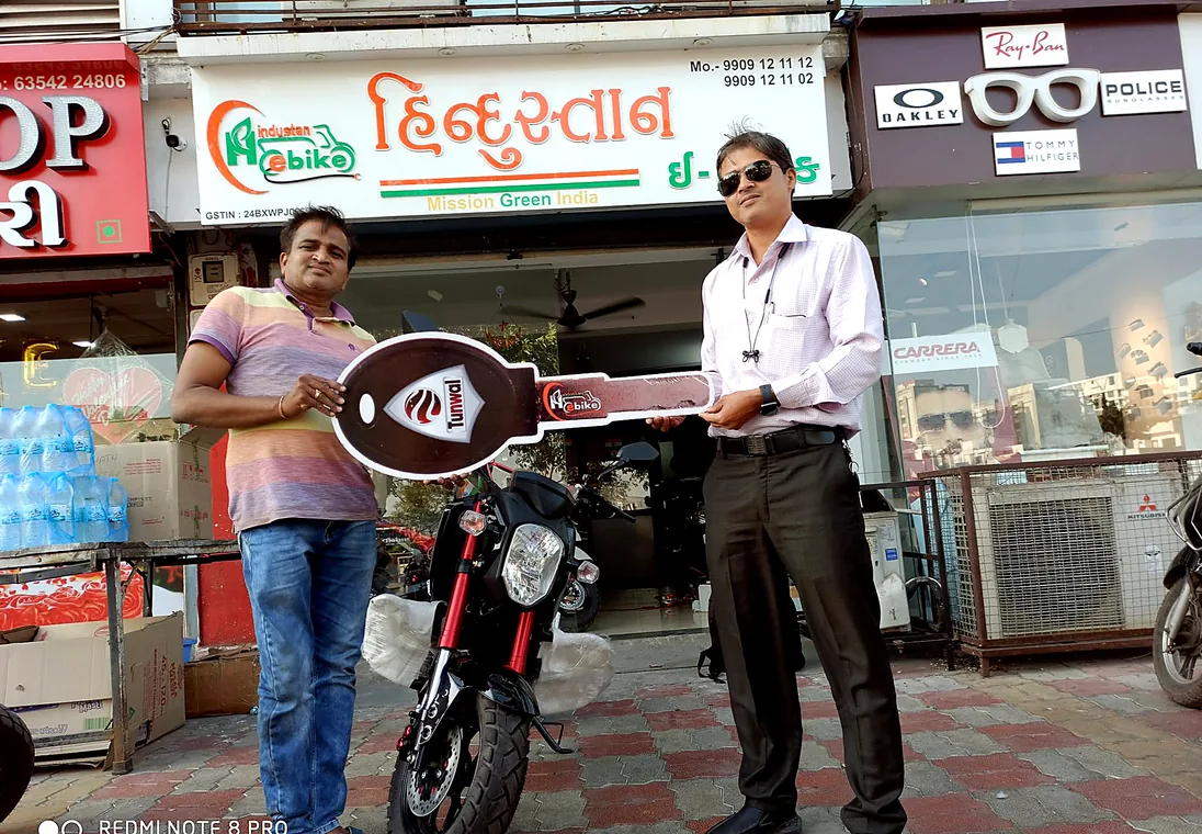 A customer collecting a black electric motorcycle outside the showroom